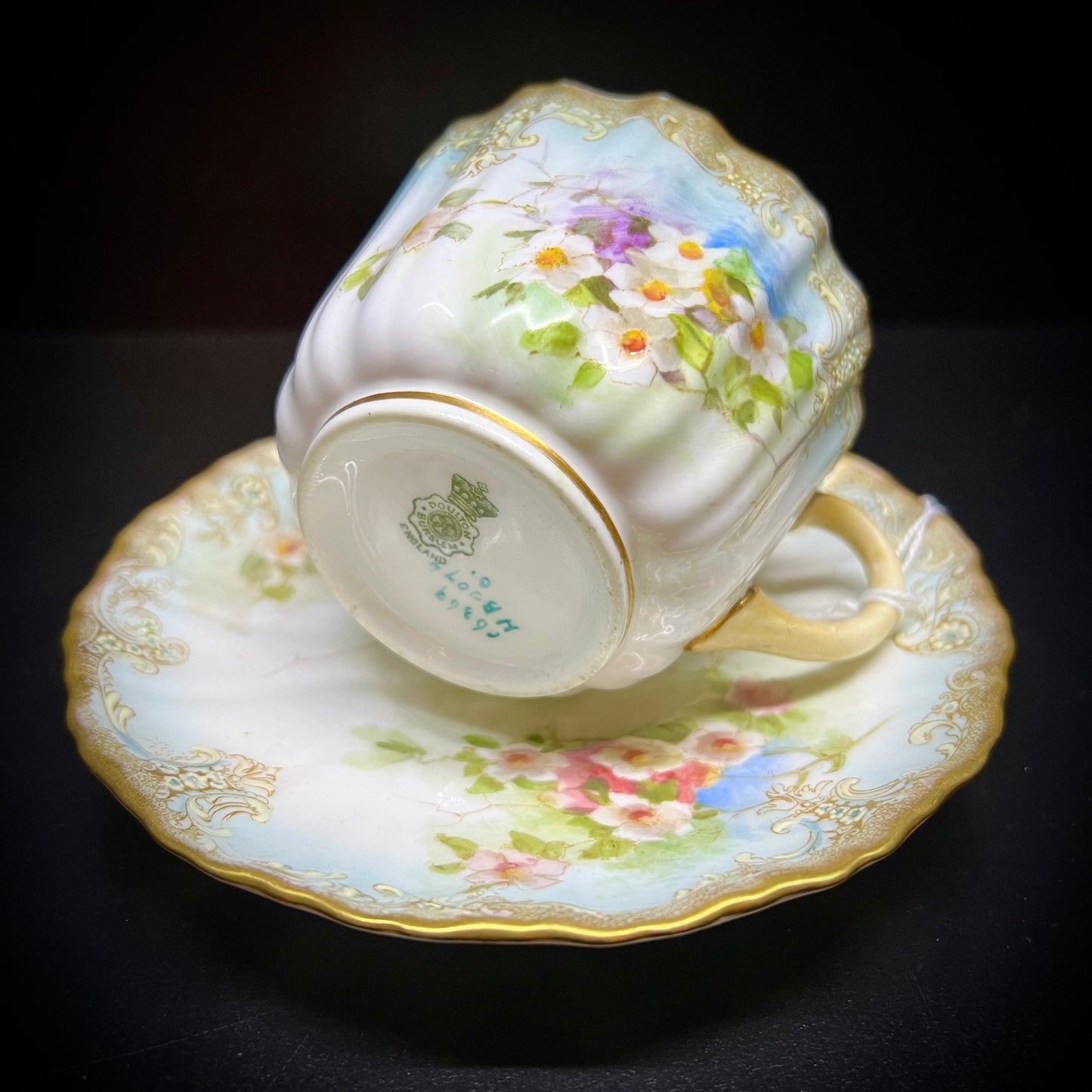 Victorian teacup and saucer decorated with rich bouquets of white flowers and raised enamel
