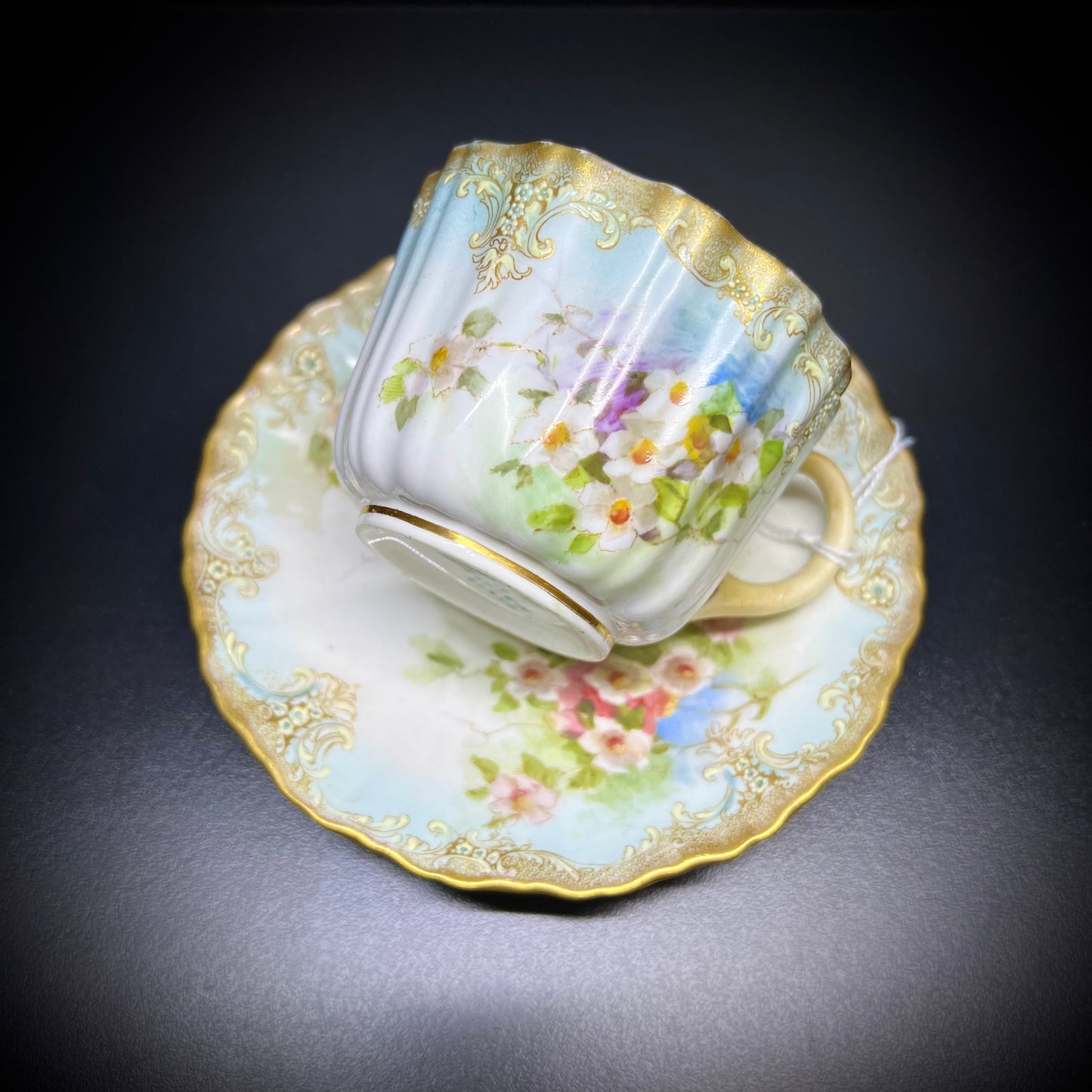 Victorian teacup and saucer decorated with rich bouquets of white flowers and raised enamel