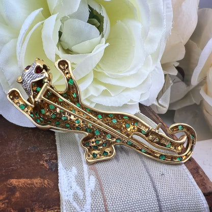 Spilla animalier a forma di leopardo in oro bianco e giallo 18k con pavé di diamanti, smeraldi e rubini agli occhi. Italia c. 1960