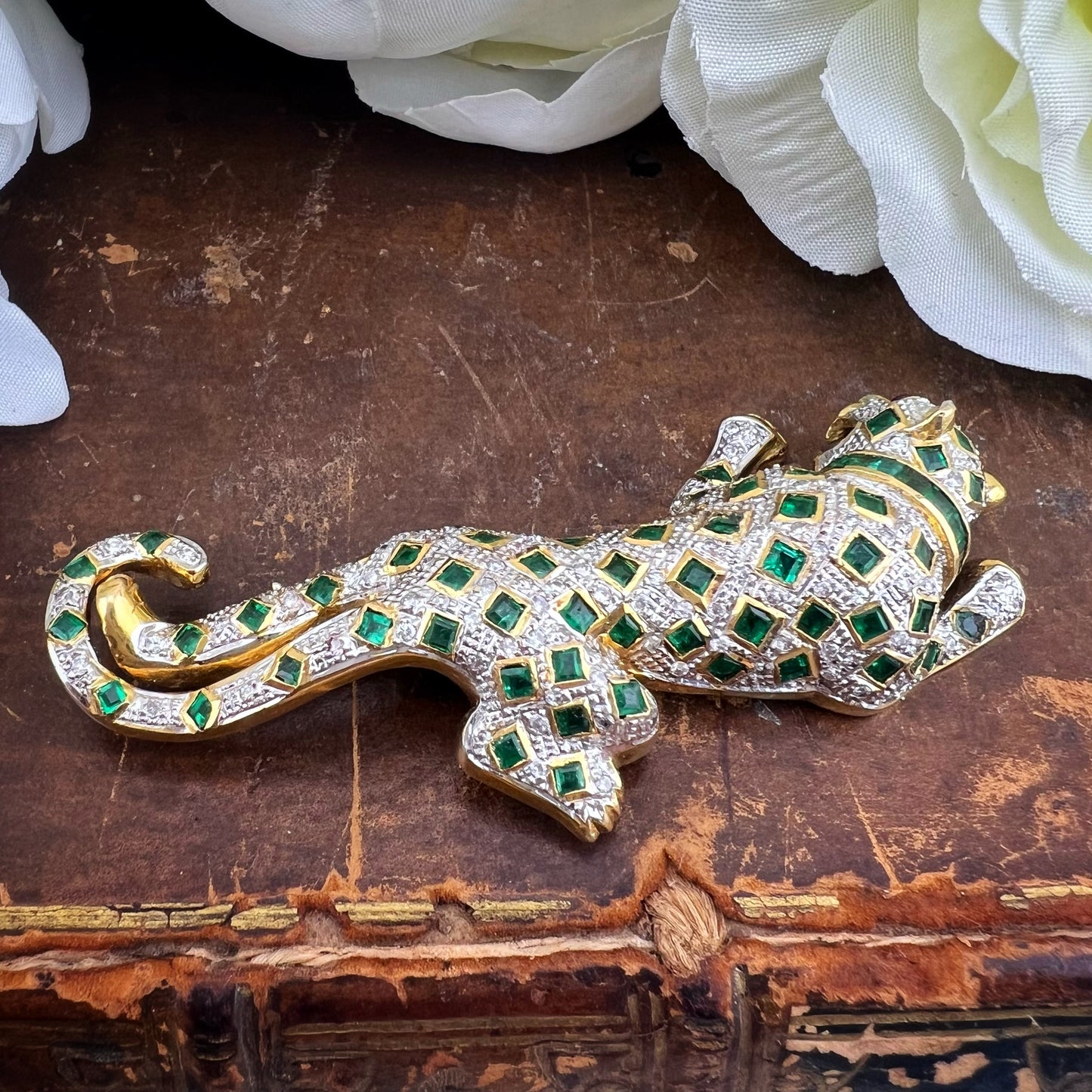 Spilla animalier a forma di leopardo in oro bianco e giallo 18k con pavé di diamanti, smeraldi e rubini agli occhi. Italia c. 1960