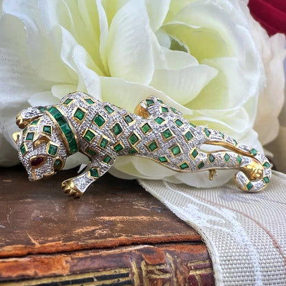 Spilla animalier a forma di leopardo in oro bianco e giallo 18k con pavé di diamanti, smeraldi e rubini agli occhi. Italia c. 1960
