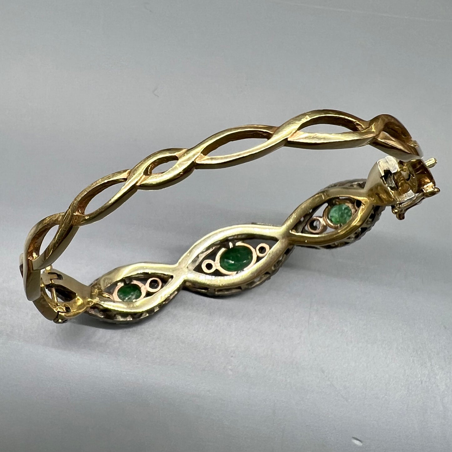 Bracciale a manetta in oro, smeraldi e diamanti a rosa.