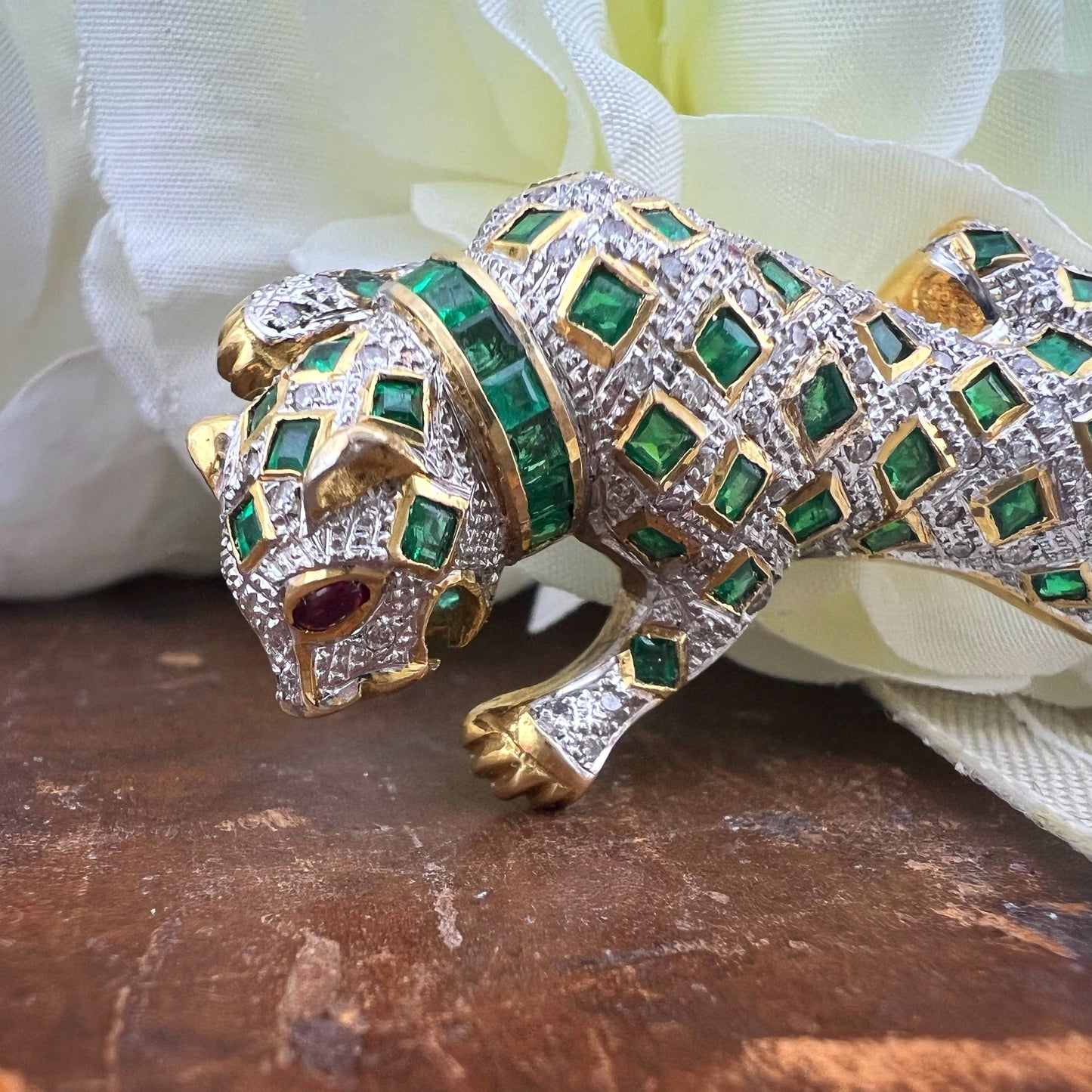 Spilla animalier a forma di leopardo in oro bianco e giallo 18k con pavé di diamanti, smeraldi e rubini agli occhi. Italia c. 1960