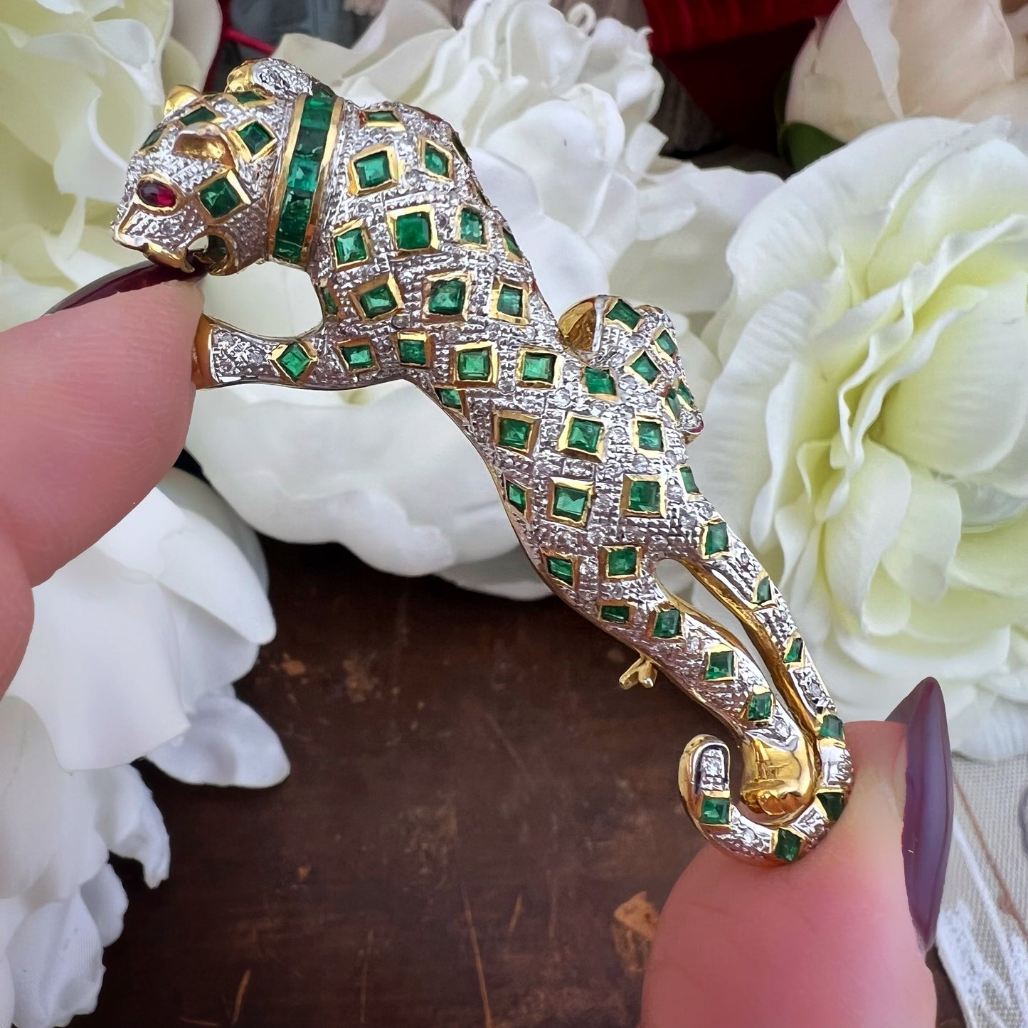 Spilla animalier a forma di leopardo in oro bianco e giallo 18k con pavé di diamanti, smeraldi e rubini agli occhi. Italia c. 1960