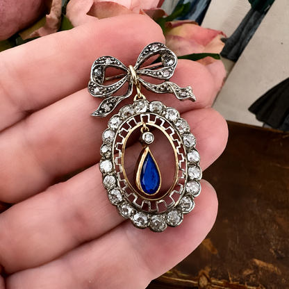 Deliziosa spilla Belle Époque in oro con fiocco, diamanti old mine e zaffiro pendente