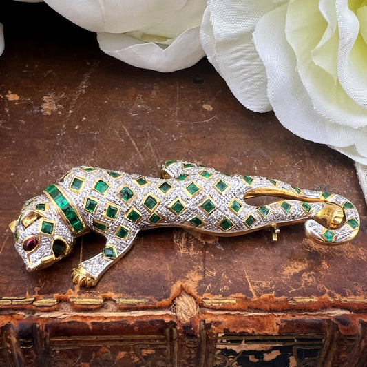 Spilla animalier a forma di leopardo in oro bianco e giallo 18k con pavé di diamanti, smeraldi e rubini agli occhi. Italia c. 1960
