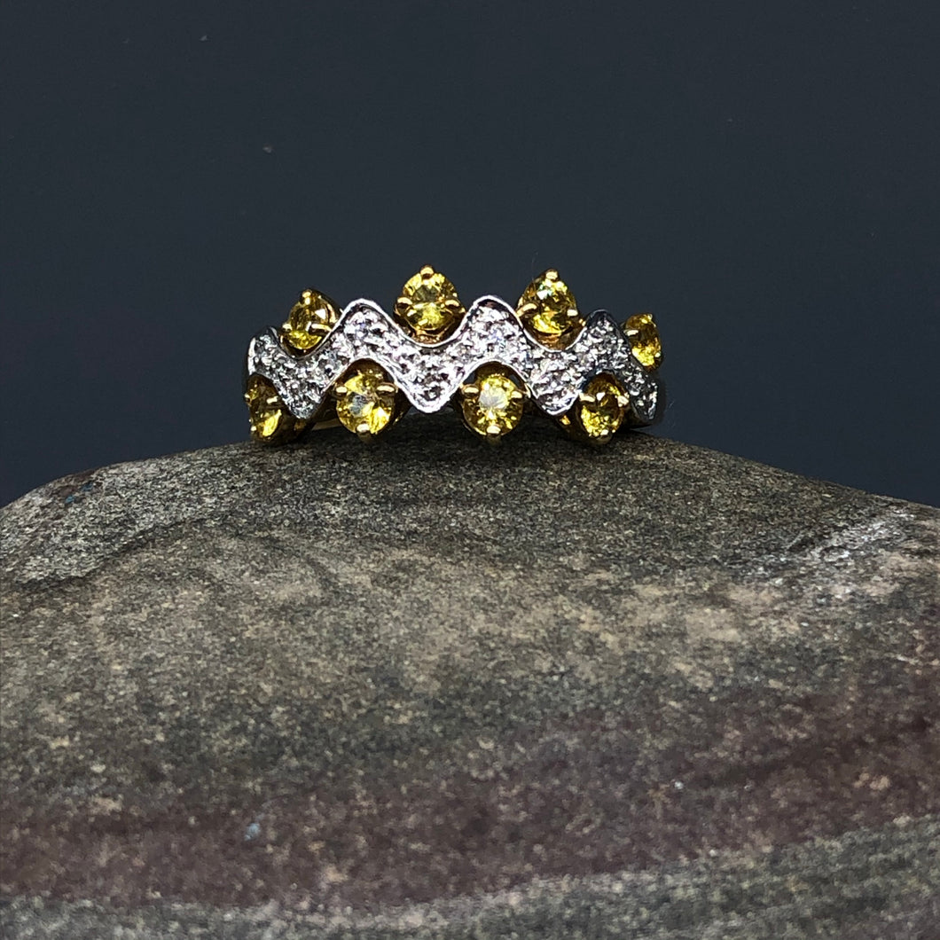 Particolare anello a fascia con serpentina di diamanti e zaffiri gialli nelle anse